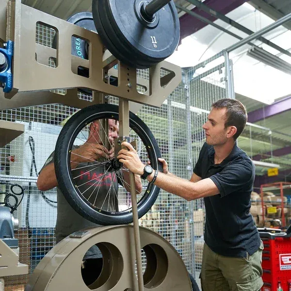Deux ingénieurs Mach1 installant une roue complète sous une pile de masses sur un banc d'essai