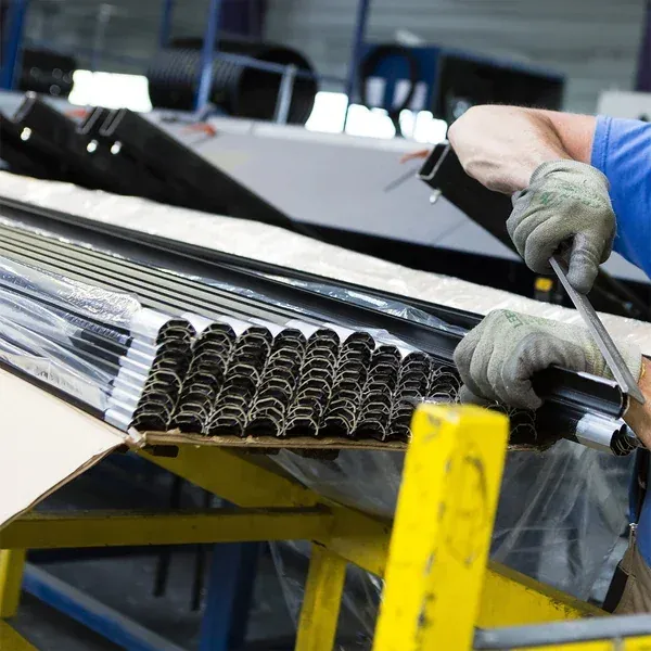 Opérateur saisissant des profilés d'aluminium dans leur carton